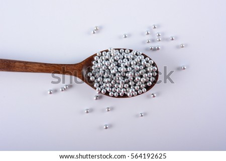 Silver Sugar Pearls on a wooden spoon. Selective Focus.