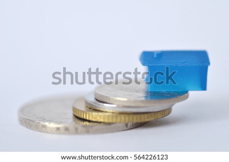 Little plastic house on metal coins, real estate and property concept