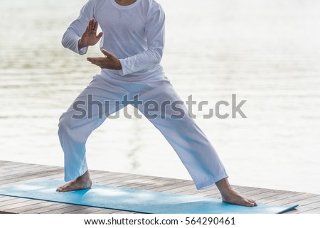 Young man practicing traditional Chinese Tai Chi, boxing, Tai Ji Chuan,   and Qi gong in the park for healthy, traditional chinese martial arts concept. Royalty-Free Stock Photo #564290461