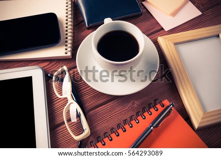 Still life photo of tablet notepad coffee glasses and other stuff on wooden table