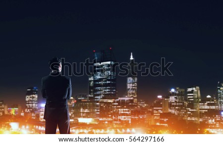 Elegant businessman with suitcase looking at night city