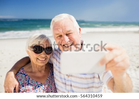 Senior couple taking selfie on the beach