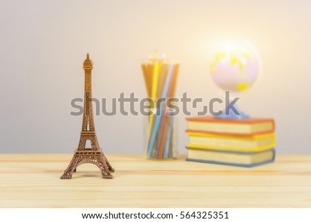 Eiffel tower statue and stack of book ,color pencil and globe on the school desk,knowledge school background education concept 