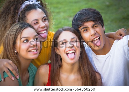 Group of happy teenagers in the park having fun spending time