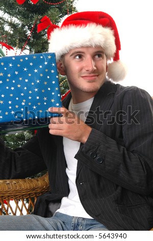 A handsome young man shaking a Christmas gift to guess what is in it