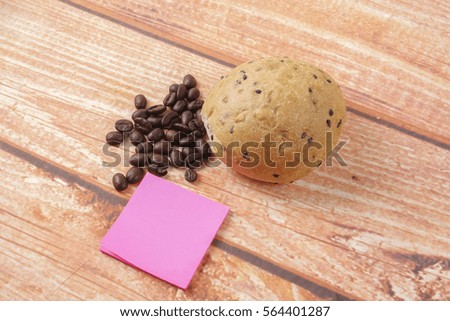 Morning breakfast concept with coffee,bun, post it notes on wooden background.