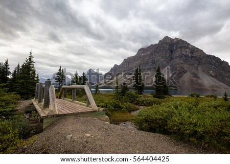 Beautiful landscape of Bow Lake and a wooden bridge across the river. Picture taken during a cloudy summer morning in Banff National Park, Alberta, Canada.