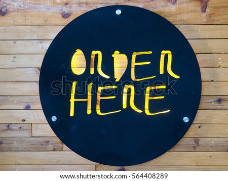 One Order here sign, black color, yellow light on wood wall 