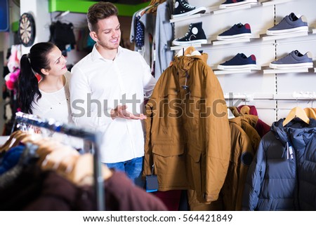 couple choosing new coat in sports store