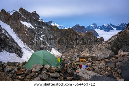 Lonely mountaineers camp in very high snowy moutains beside glacier. Picture was taken during a trekking hike in wonderful  mountains of northern Caucasia , Bezengi region, Kabardino-Balkaria, Russia