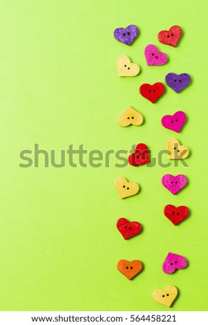 Heart shaped colorful wooden sewing buttons on greenery background as frame. Copy space for text. Top view