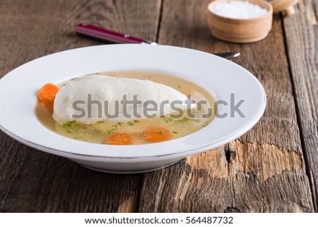 Homemade chicken broth. Golden stock served  in white plate with  breast on rustic wooden table 