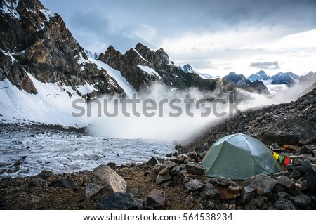 Lonely mountaineers camp in very high snowy moutains beside glacier. Picture was taken during a trekking hike in the amazing and gorgeous Caucasus mountains, Bezengi region, Kabardino-Balkaria, Russia