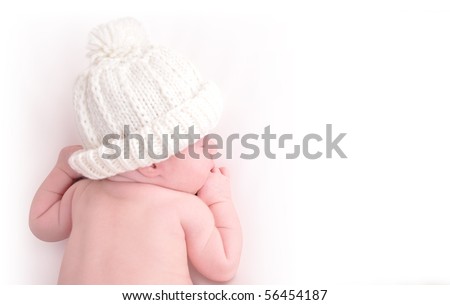 A newborn baby is wearing a white hat and laying down sleeping on a white isolated background. Use the photo to represent life, parenting or childhood. Royalty-Free Stock Photo #56454187