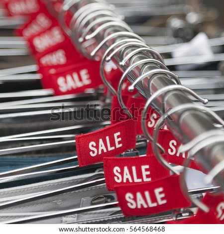 red labels with the word sale on clothes hangers outside fashion store