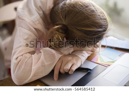 Tired woman lying on a table with a graphic tablet