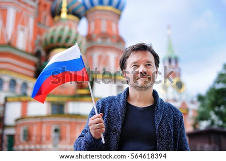 Middle age man holding russian flag with Saint Basil's Cathedral on background 