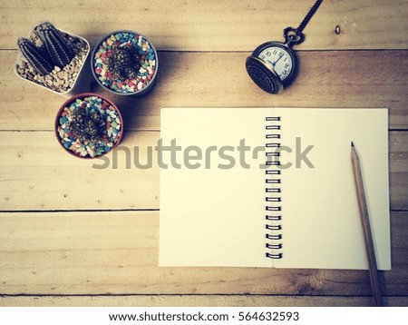 Notebook, pencil, pocket watch and cactus on old wood table, process vintage tone