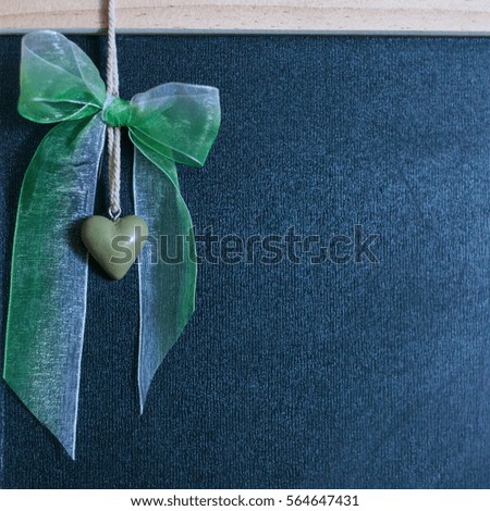 Valentine's Day, 14 February, a green heart on a string on a black background and bow