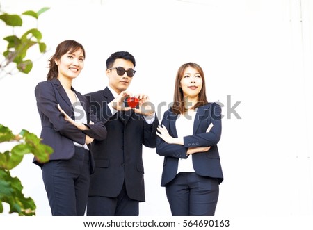 Smart man is holding heart shape in hand. He is standing between two smart woman on white background.