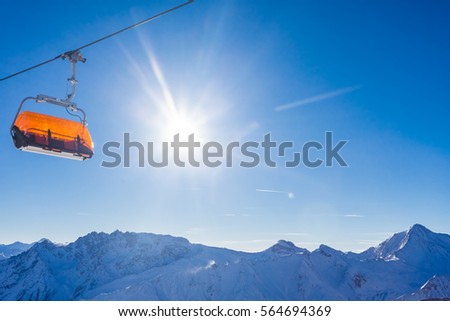 Empty orange chairlift panorama with mountains and blue sky in the background, snow and sun with no people, winter picture of Samnaun, Swiss Alps, Switzerland, Europe.