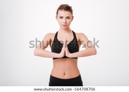 Portrait of a fitness pretty young woman with hands together standing in meditation position and looking at camera isolated on white background