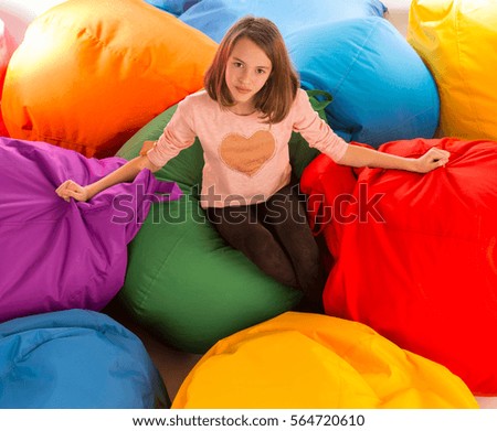 Young happy girl sitting between beanbag chairs and looking at the camera