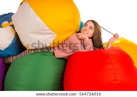 Young dreaming woman lying between beanbag chairs isolated on white background