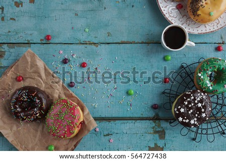 Homemade colorful donuts and black coffee  on rustic turquoise wooden background. Delicious breakfast, overhead view, selective focus