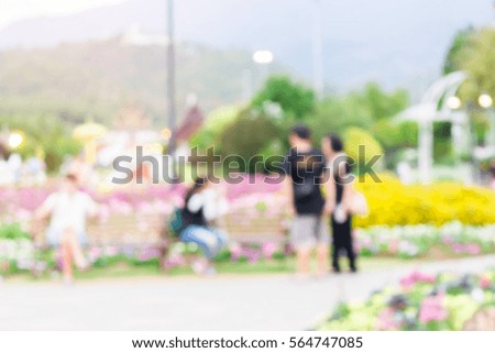 blurred image of people in the park in the evening with colorful flowers