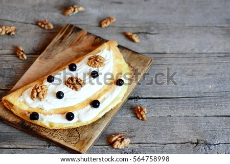 Fried crispy omelette with sweet filling. Home omelette with soft cheese and shelled walnuts on a wooden background with empty place for text. Quick dish using egg. Closeup