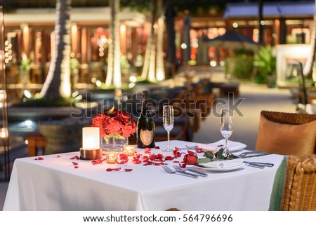 Pool side Candlelight Dinner and Romantic Sunset Dining table setup for couple with bottle of champagne Royalty-Free Stock Photo #564796696