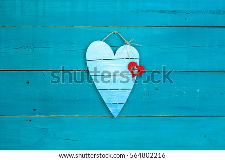 Blank broken heart shaped sign with red heart hanging on rustic antique teal blue wood background; Valentines Day, Mothers Day and love concept with painted copy space
