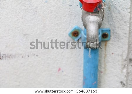 faucet old with water drop in wall cement background