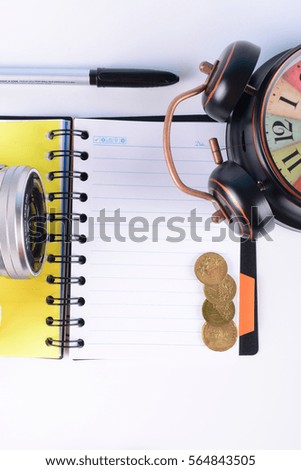 Business Concept. Top view of small camera, alarm clock, pen and open notebook isolate on white background.