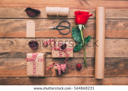 Beautiful gifts with flowers and decorative rope, on old wooden background