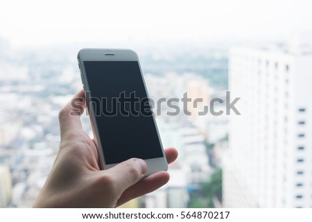 Man hand holding mobile phone or smart phone with building view in the background