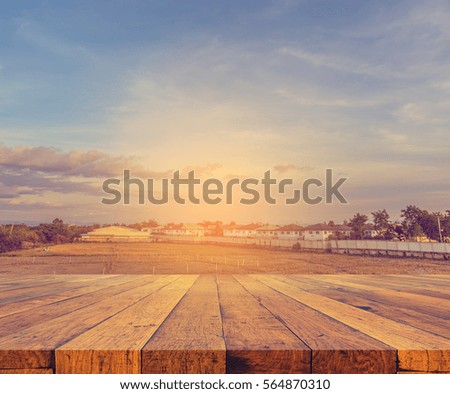 old wooden table with vintage tone image of village and sunset sky in background