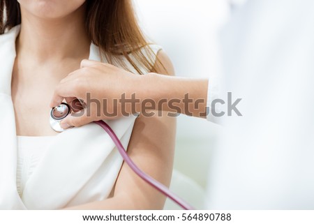 Doctor using stethoscope to exam woman patient heart Royalty-Free Stock Photo #564890788