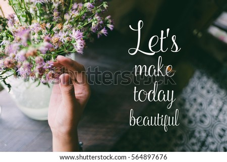 Love quote. Motivation quote on soft background. The hand touching purple flowers. Let's make today beautiful.