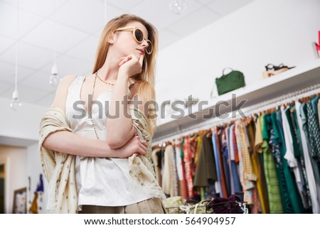 Young smiling pretty woman shopping in dress store