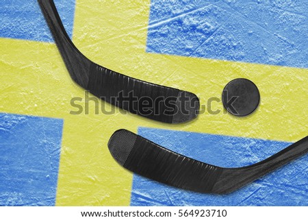 Hockey puck, hockey sticks and a picture of the Swedish flag on the ice. Concept