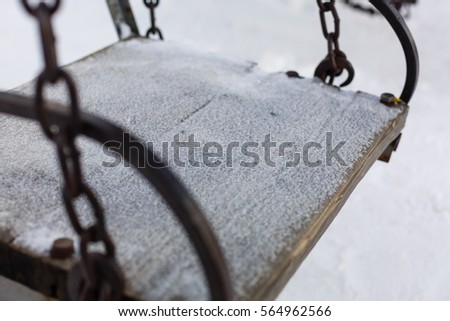 Abstract winter scene with a garden swing covered snow, appearing to invite everyone take break, have snack and enjoy the landscape generally the unique moments of the life.