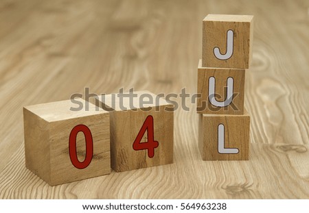 Cube shape calendar for JULY 4 on wooden surface. 