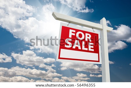 For Sale Real Estate Sign over Clouds and Blue Sky with Sun Rays.