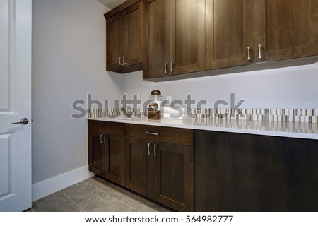 Laundry room interior features blue and grey walls framing brown cabinets, mosaic backsplash and grey tile flooring. Northwest, USA
