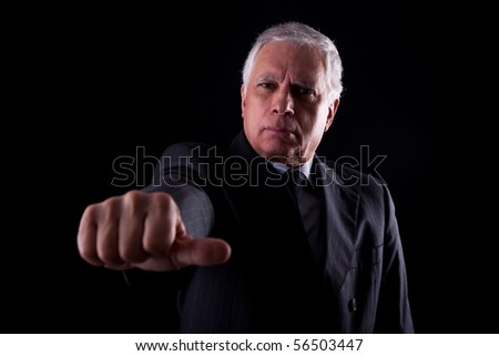 old businessman with a hand with thumbs middle on black background, studio shot