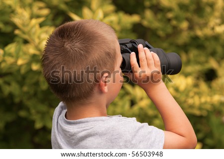 young boy is watching through field glasses