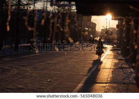 silhouette of walking woman with bags in sunrise time empty street