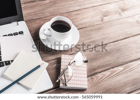 Still life photo of laptop notepad coffee glasses and other stuff on wooden table